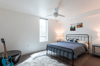 a bedroom with a bed and a guitar and a ceiling fan