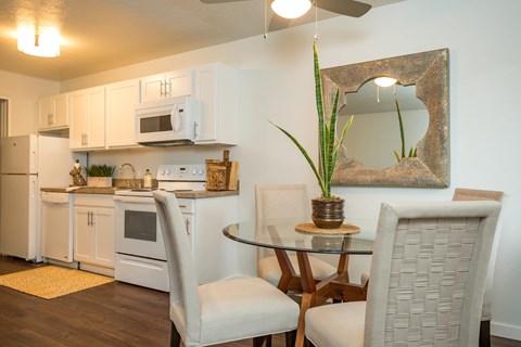 A white kitchen with a glass table and chairs.