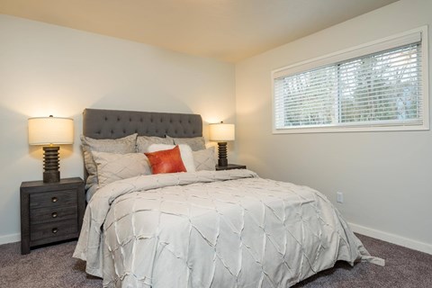 A bedroom with a bed, nightstand, and window.