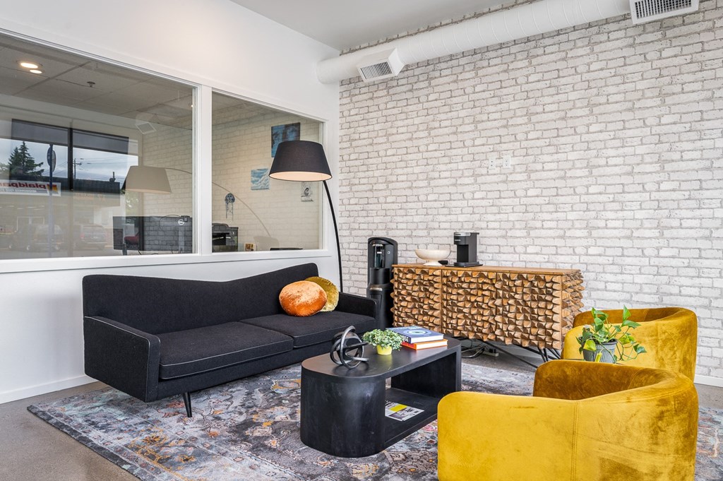 a living room with a black couch and yellow chairs