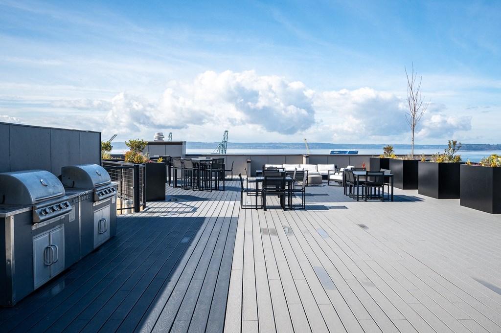 a rooftop patio with tables and chairs and a view of the ocean