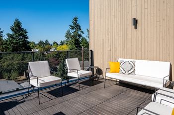 a patio with two white chairs and a white couch on a balcony