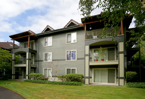 A grey two story apartment building with balconies.