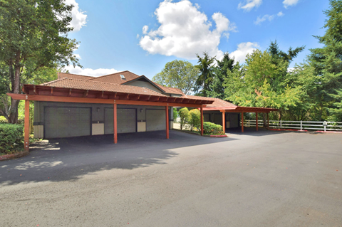 A large building with a red roof and a parking lot in front.