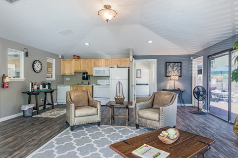 a living room with two chairs and a table and a kitchen
