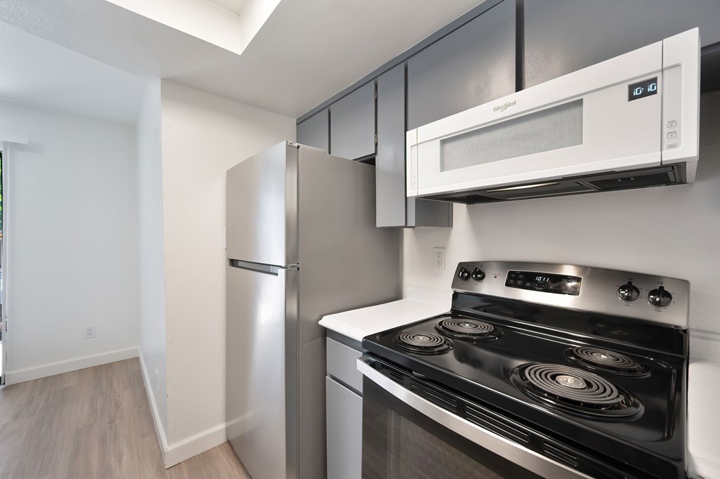A kitchen with a stove, refrigerator, and microwave.