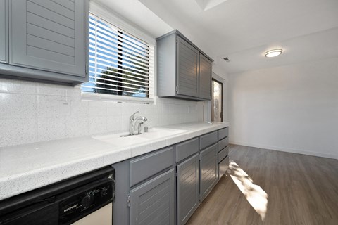a kitchen with white counter tops and gray cabinets