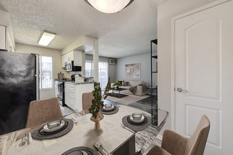 A kitchen with a table set for two with a plant on it.