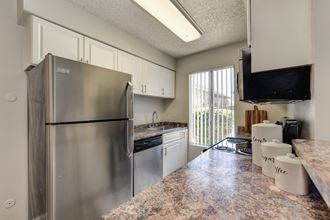 Kitchen with stainless steel appliance package, white cabinetry and ample counter space