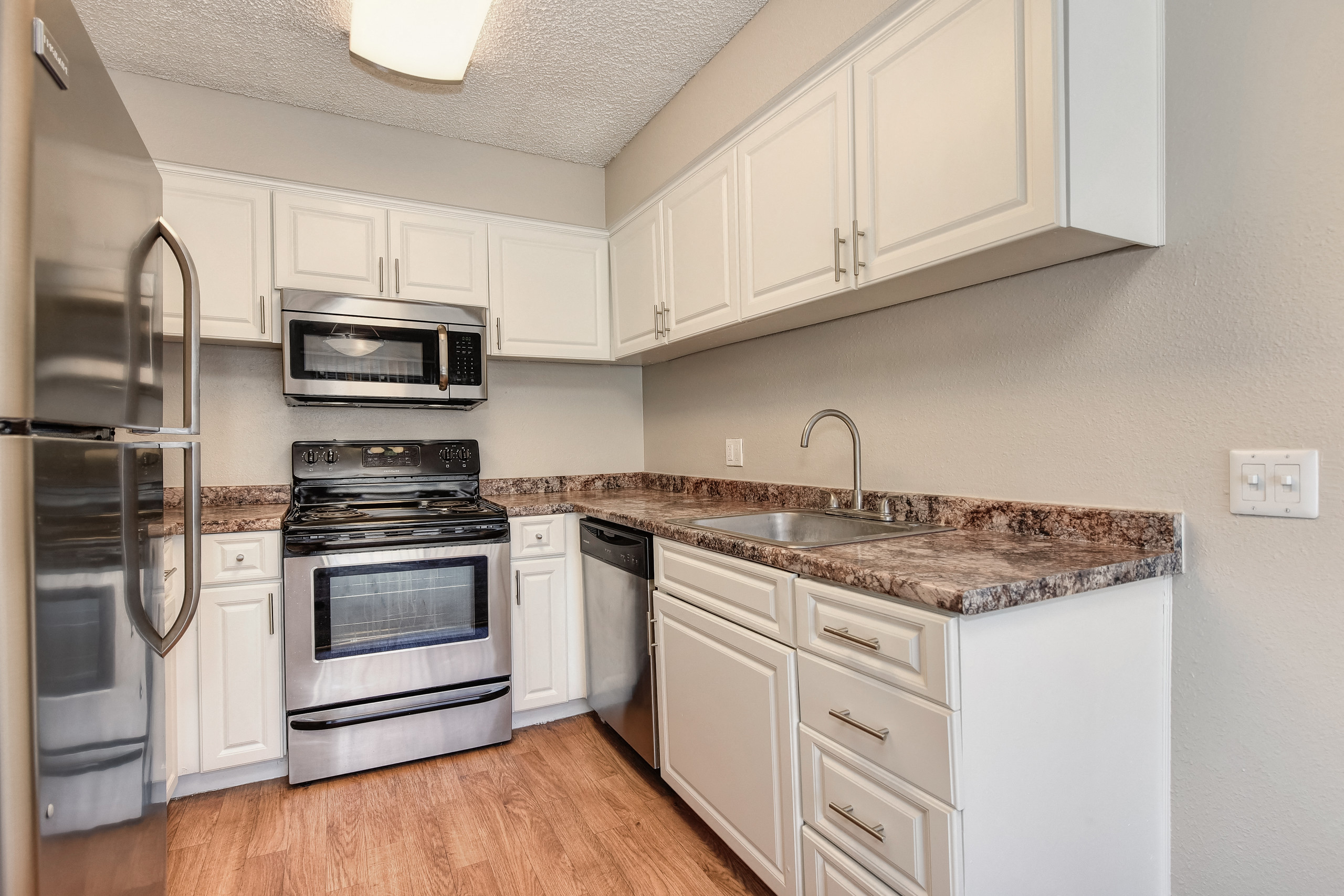 Kitchen with white cabinetry, stainless steel sink, faucet and cabinet hardware