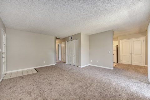 A spacious room with carpeted floor and white walls.