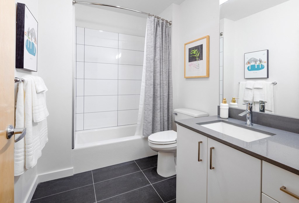 Luxury 1 BR Apartments in Portland OR - Couch9 Apartments - Bathroom with Large Mirror, White Cabinetry, and Large Grey Tile Flooring