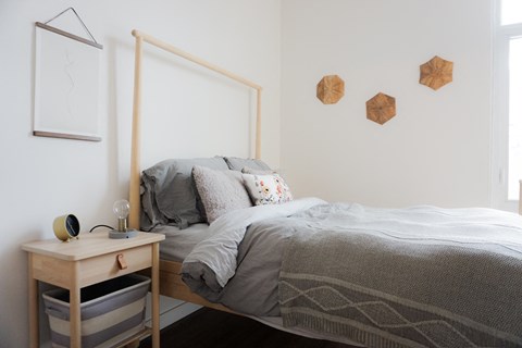 a bedroom with a bed and a mirror and a nightstand next to it