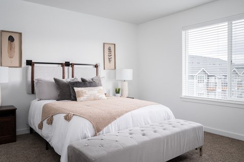 a bedroom with a bed and an ottoman in front of a window