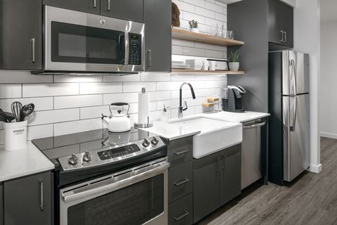 Luxury 2 BR Apartments in Portland OR - Couch9 Apartments - Modern Kitchen with Stainless Steel Appliances, Quartz Countertops, Tile Backsplash, Grey Cabinetry, and Hardwood Flooring