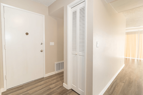 A white door with a brown knob is in a room with a white wall and a white radiator.