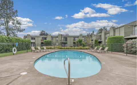 A swimming pool surrounded by a fence and chairs.