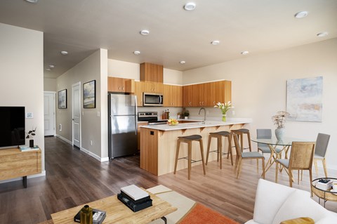 an open kitchen and living room with a bar and stools