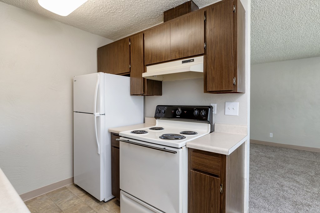 A kitchen with a white stove and refrigerator.