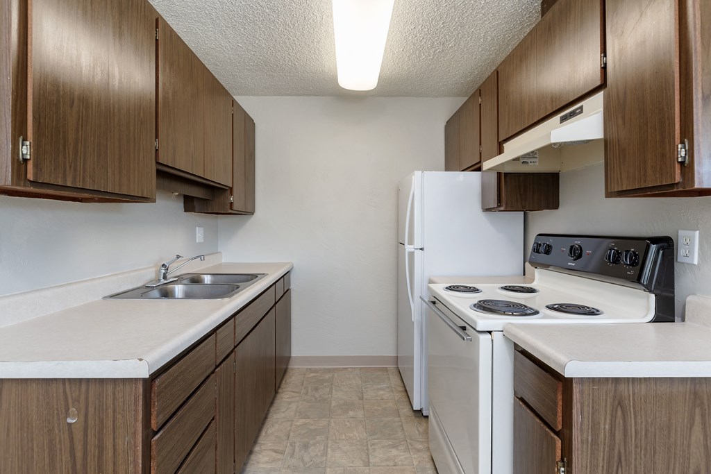 A kitchen with white appliances and brown cabinets.