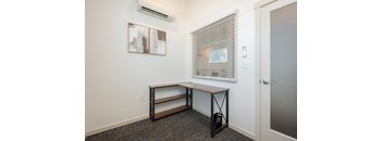 A room with a window, a bench, and a painting on the wall.