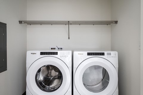 Two white Whirlpool washing machines in a laundry room.