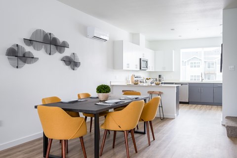 A modern dining room with a black table and yellow chairs.