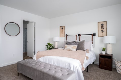 A bedroom with a large bed and a grey ottoman.