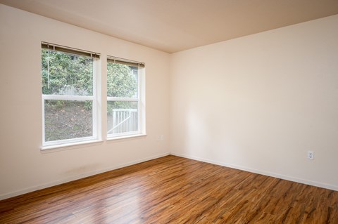 A room with wooden floors and two windows.