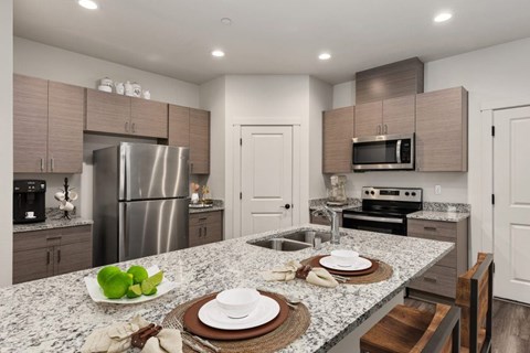 A modern kitchen with granite countertops and stainless steel appliances.