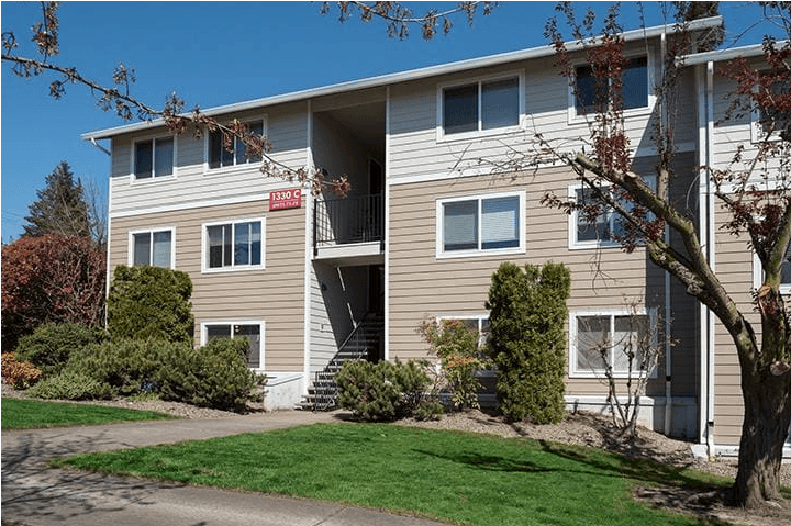 a large apartment building with tan siding and a red sign on the side of the building