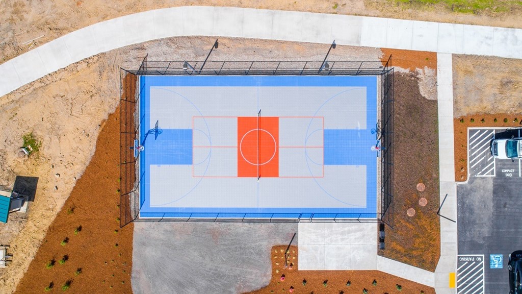 A basketball court is surrounded by a fence and a wall with a pattern of circles.