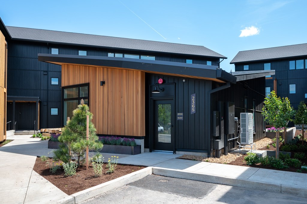 A modern building with a black exterior and a wooden entrance.