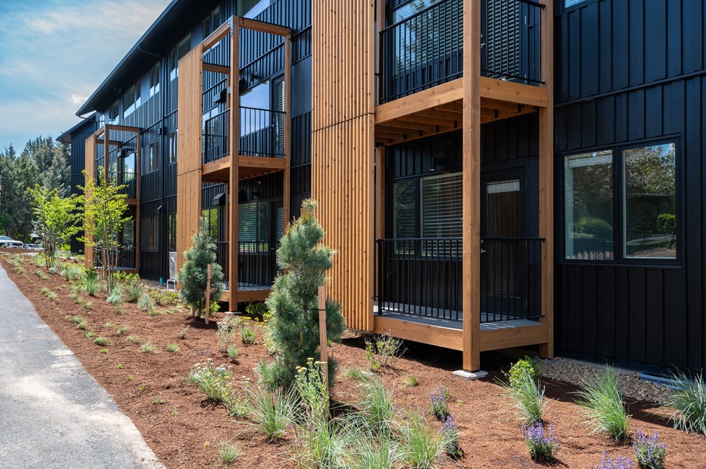 A modern building with a black exterior and wooden balconies.