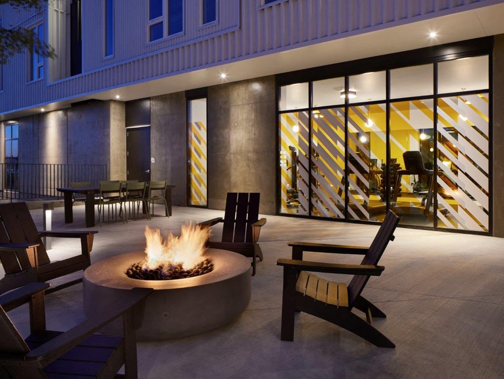 a firepit and chairs on a patio in front of a building