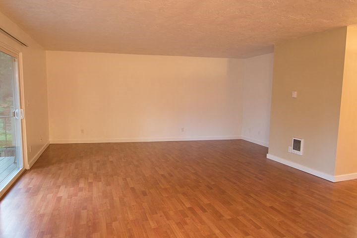 an empty living room with wooden floors and a window