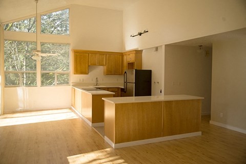 an empty kitchen with wood floors and a large window