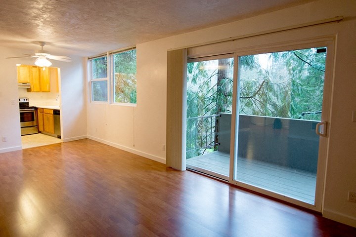 an empty living room with a sliding glass door to a deck