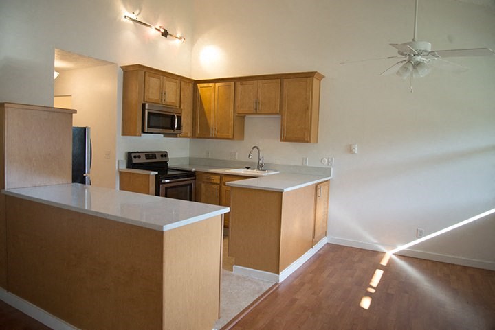 an empty kitchen with wooden cabinets and white counter tops