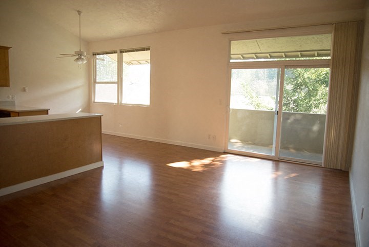an empty living room with wood floors and a sliding glass door