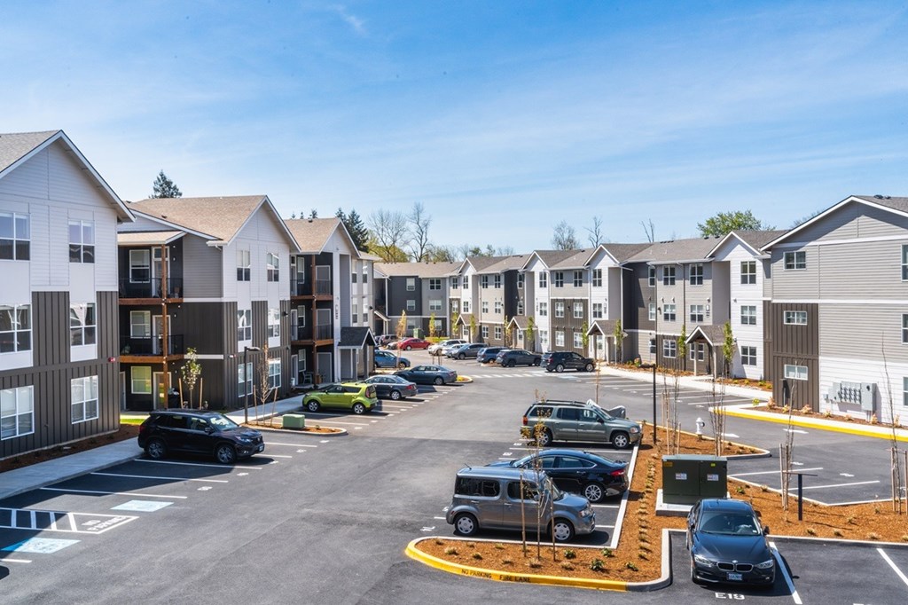 A parking lot with cars and apartment buildings in the background.