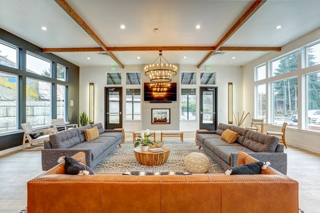 A large, well-lit living room with a central sectional sofa and a chandelier hanging from the ceiling.