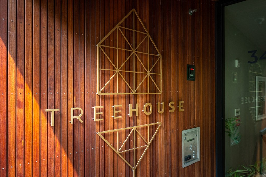 the facade of the treehouse is lit up at night with three geometric shapes on