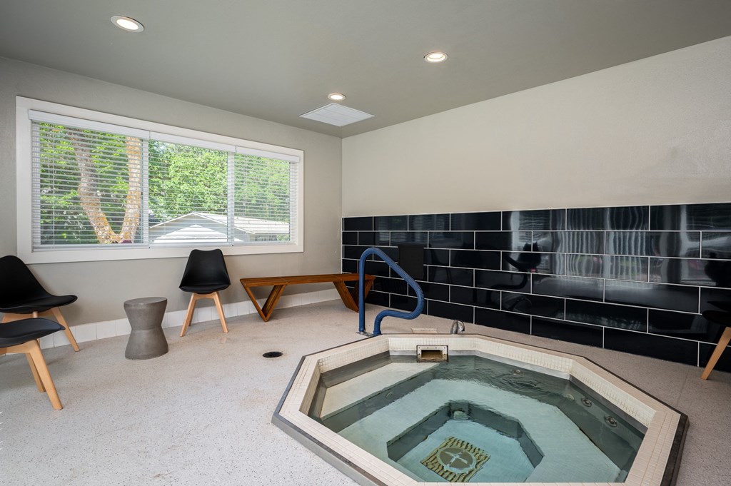 a spa with a hot tub in a room with chairs and a window