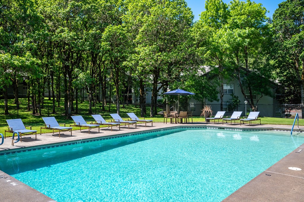 the pool is surrounded by lawn chairs and trees