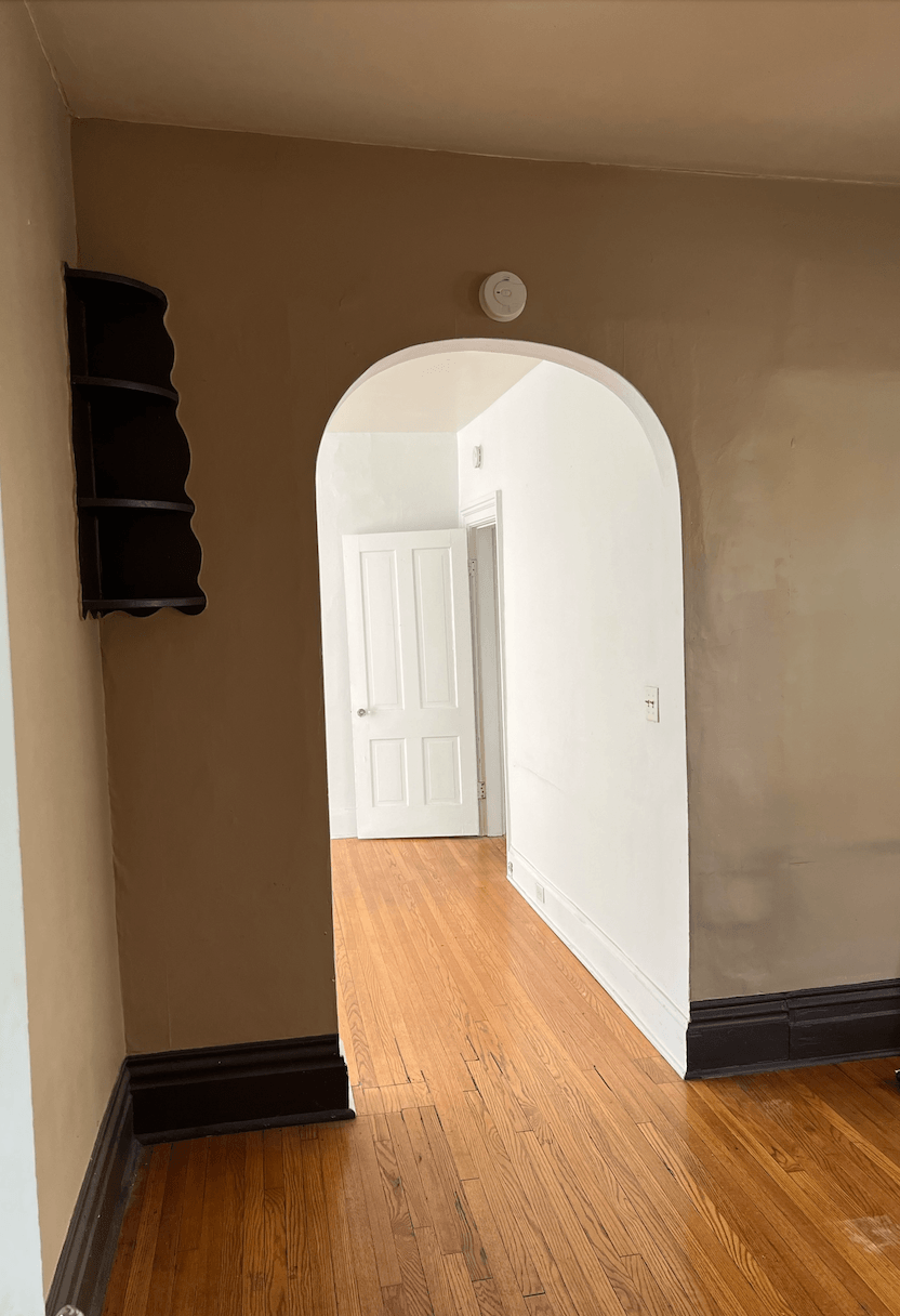 an arched doorway in a room with white walls and hardwood floors