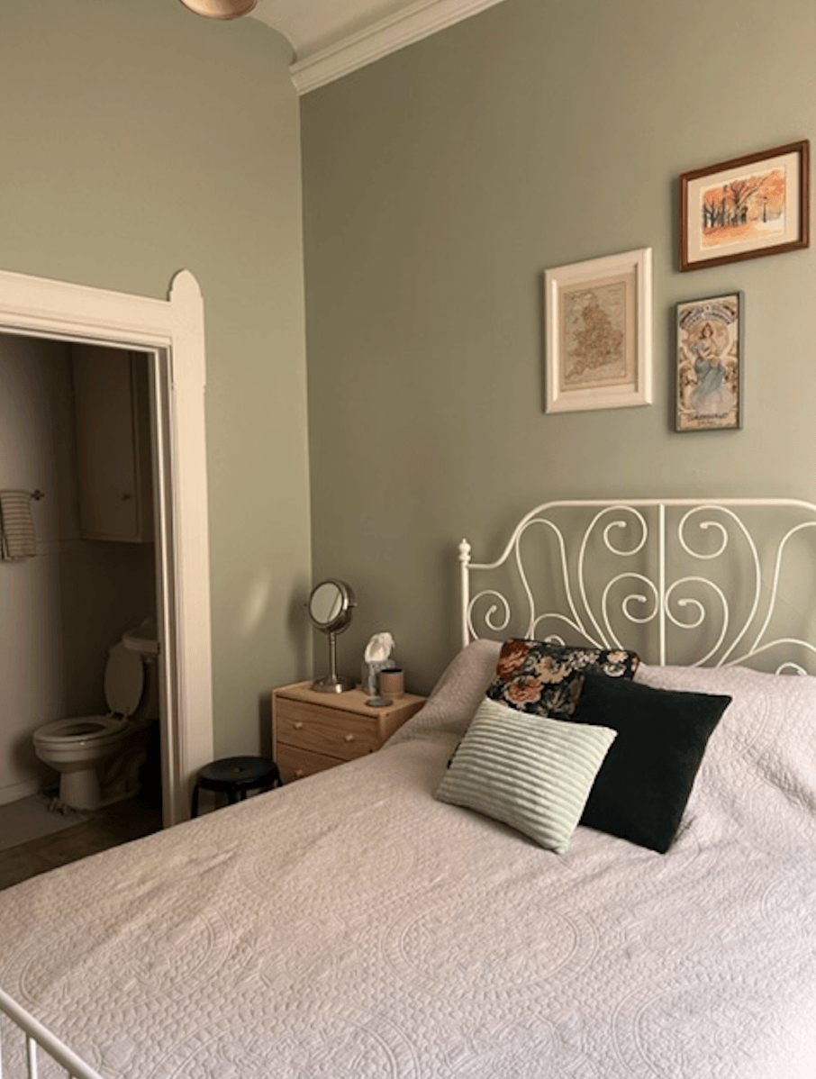 a bedroom with a bed and a nightstand with a mirror on it
