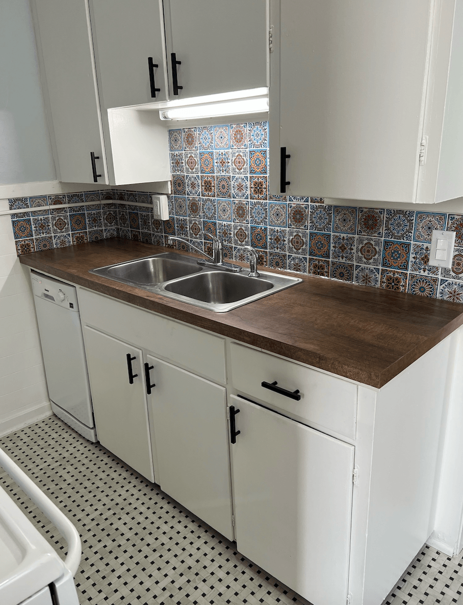 a small kitchen with white cabinets and a wooden counter top