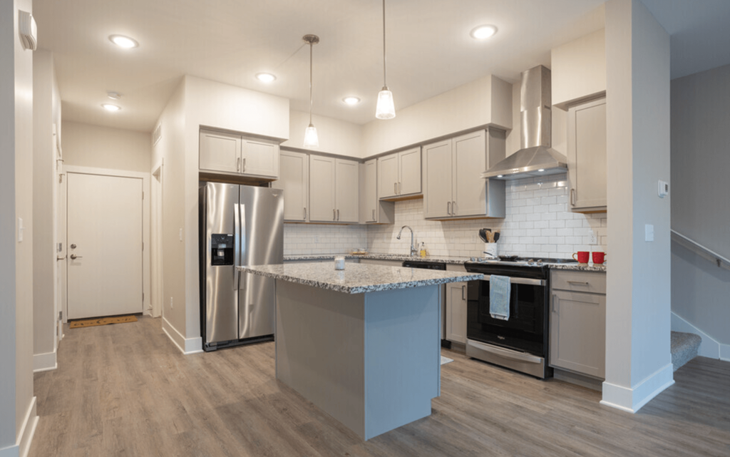 A kitchen with a stainless steel refrigerator and a range hood.