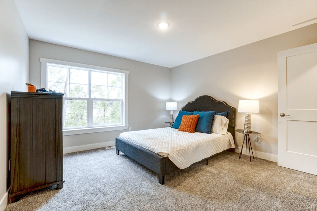 A bedroom with a bed, dresser, and window.